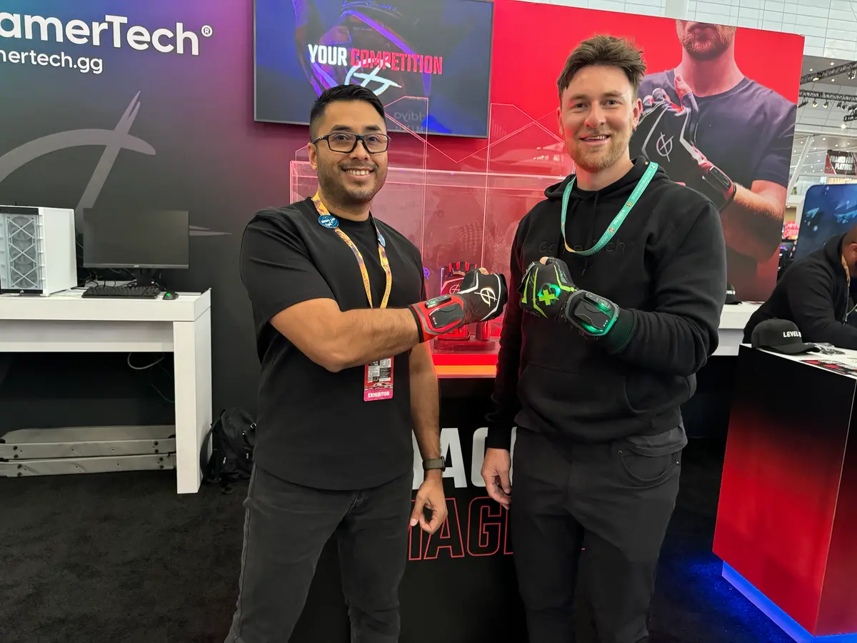 Two men fist-bumping, each wearing a Magma Glove, at the GamerTech exhibition stand