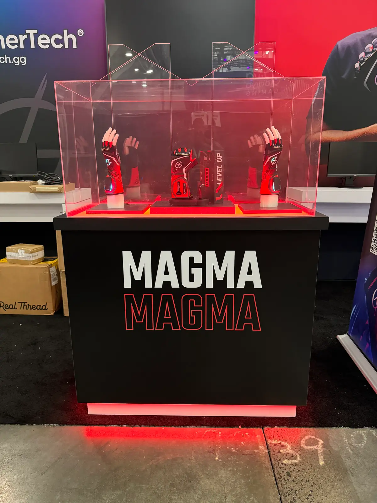 A pair of Magma Gloves in a lit display case on a Magma branded plinth